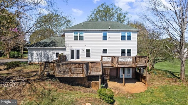 rear view of house featuring a wooden deck, a patio area, french doors, and a shingled roof