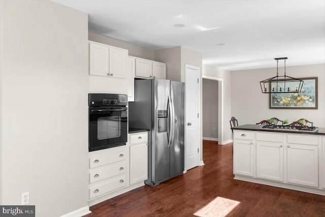kitchen with stainless steel fridge, black oven, dark countertops, dark wood-style floors, and white cabinetry