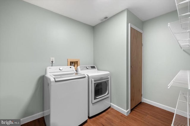 laundry room with separate washer and dryer, light wood-style floors, and baseboards