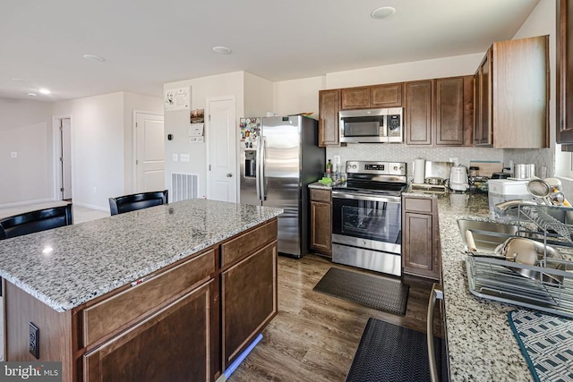 2612 High Pt, Culpeper, VA 22701 - kitchen featuring appliances with stainless steel finishes, wood finished floors, light stone countertops, a center island, and tasteful backsplash