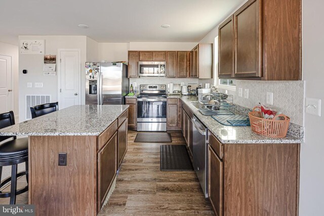2612 High Pt, Culpeper, VA 22701 - kitchen with stainless steel appliances, wood finished floors, a kitchen bar, light stone countertops, and a kitchen island