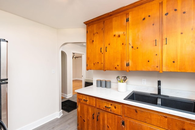 123 Fraser Ln, Staunton, VA 24401 - kitchen featuring a sink, light countertops, light wood-style floors, baseboards, and arched walkways