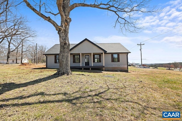 view of front facade with a shingled roof and a front lawn