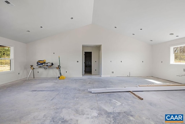 unfurnished room featuring visible vents, lofted ceiling, and a healthy amount of sunlight