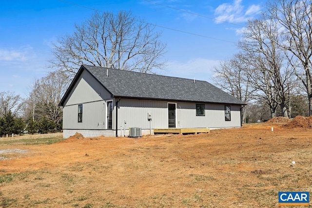 view of side of home featuring central AC and a shingled roof