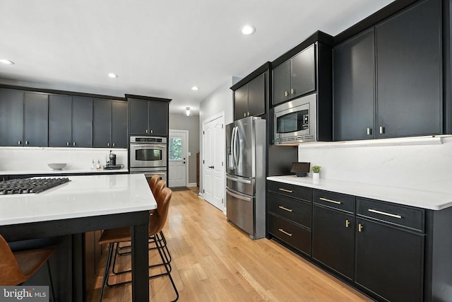 11220 Chivalry Chase Ln, Spotsylvania, VA 22551 - kitchen with stainless steel appliances, dark cabinets, light wood finished floors, recessed lighting, and light countertops