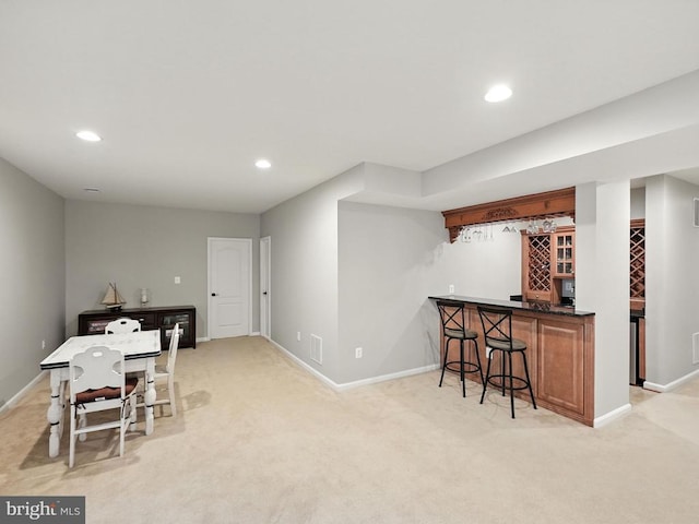 11220 Chivalry Chase Ln, Spotsylvania, VA 22551 - kitchen with light carpet, recessed lighting, a breakfast bar, brown cabinetry, and dark countertops