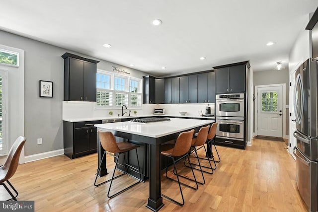 11220 Chivalry Chase Ln, Spotsylvania, VA 22551 - kitchen with stainless steel appliances, light countertops, a breakfast bar area, light wood finished floors, and recessed lighting