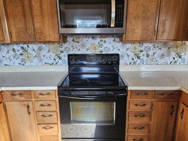 508 Stuart Ave N, Elkton, VA 22827 - kitchen featuring stainless steel microwave, black range with electric stovetop, light countertops, and brown cabinets