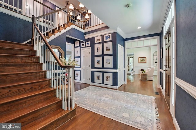 - foyer entrance featuring stairs, a chandelier, crown molding, wood finished floors, and baseboards