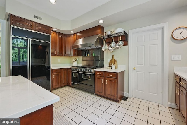  - kitchen with black appliances, wall chimney range hood, light countertops, recessed lighting, and light tile patterned floors