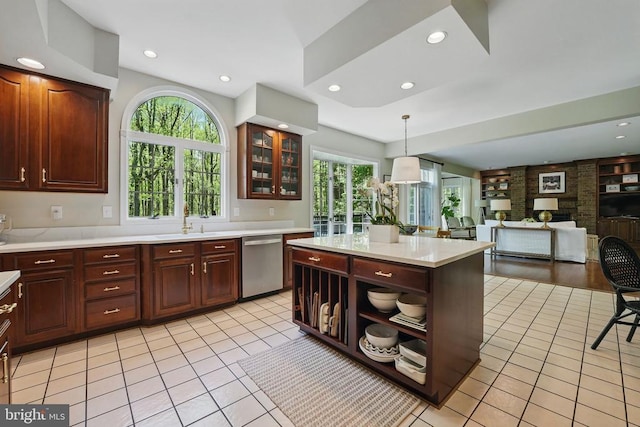  - kitchen with stainless steel dishwasher, light countertops, light tile patterned floors, hanging light fixtures, and glass insert cabinets