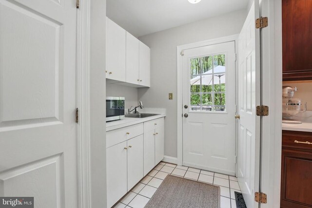  - laundry area with a sink, light tile patterned floors, and baseboards