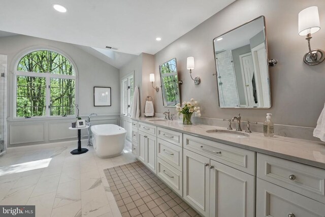  - bathroom featuring vaulted ceiling, a tile shower, marble finish flooring, a freestanding bath, and double vanity