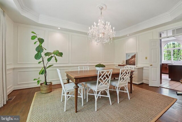  - dining space with a decorative wall, dark wood finished floors, crown molding, and a chandelier