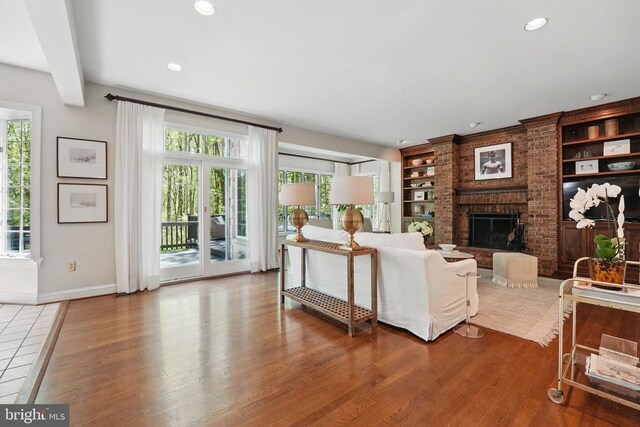  - living room featuring baseboards, a brick fireplace, wood finished floors, recessed lighting, and built in shelves
