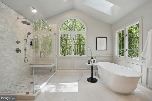  - bathroom with a shower stall, a skylight, marble look tiles, a freestanding tub, and vaulted ceiling