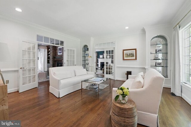  - living room with french doors, a fireplace, wood finished floors, healthy amount of natural light, and crown molding