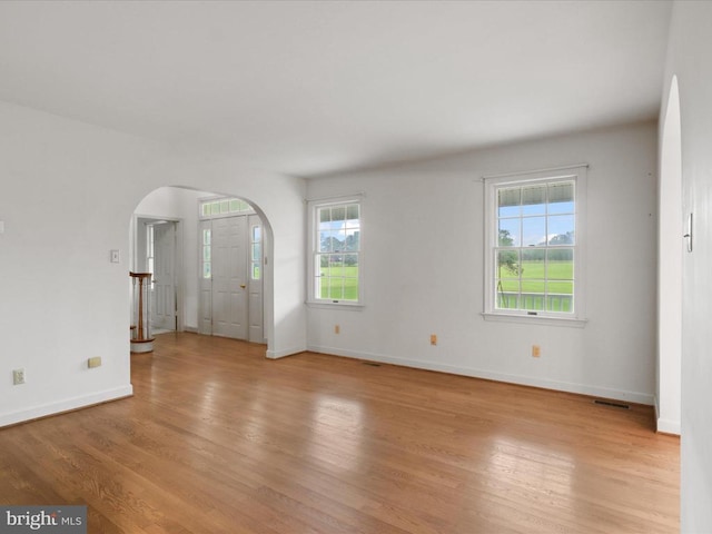  - spare room with arched walkways and light wood-type flooring