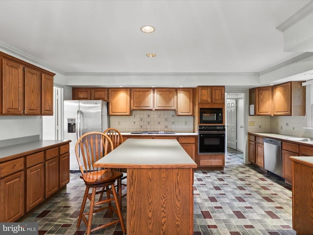  - kitchen with black appliances, decorative backsplash, a breakfast bar, brick patterned floors, and brown cabinetry