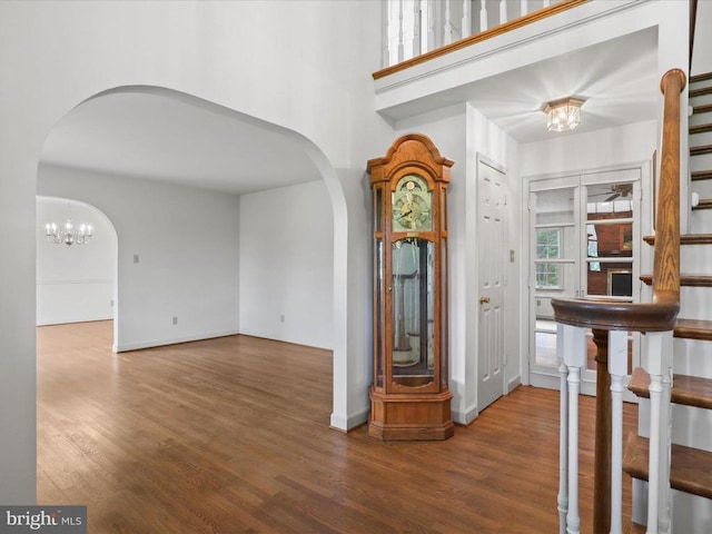  - entrance foyer with arched walkways, wood finished floors, and a chandelier