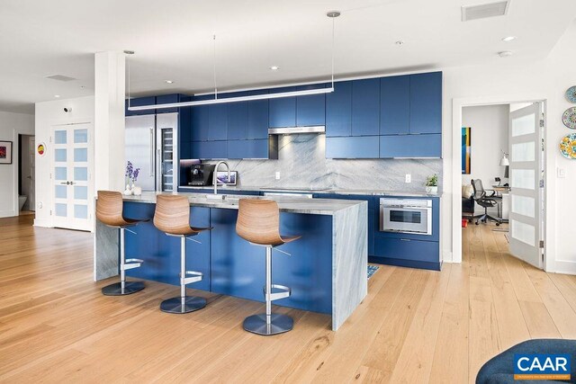 218 Water St W Unit 705, Charlottesville, VA 22902 - kitchen with stainless steel appliances, a kitchen breakfast bar, blue cabinets, and backsplash