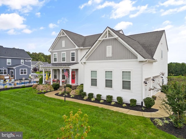 view of front of property featuring a front lawn, fence, board and batten siding, and roof with shingles