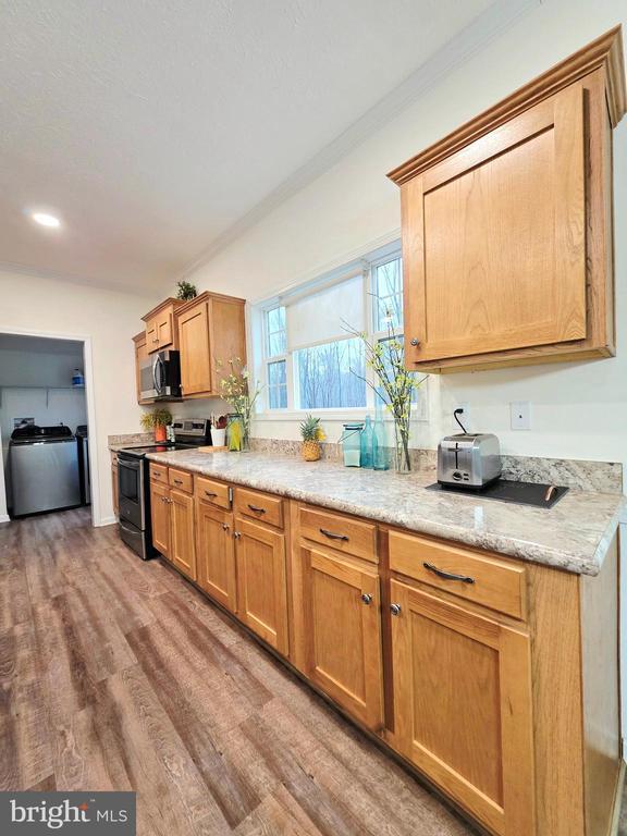 14511 Antler Rd, Fredericksburg, VA 22407 - kitchen with stainless steel appliances, wood finished floors, light countertops, ornamental molding, and recessed lighting