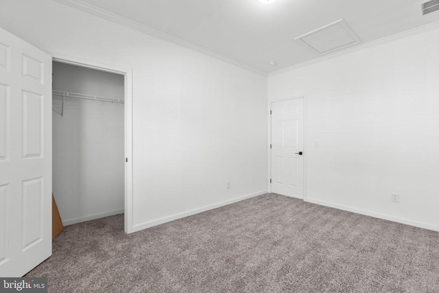 unfurnished bedroom featuring crown molding, attic access, and carpet