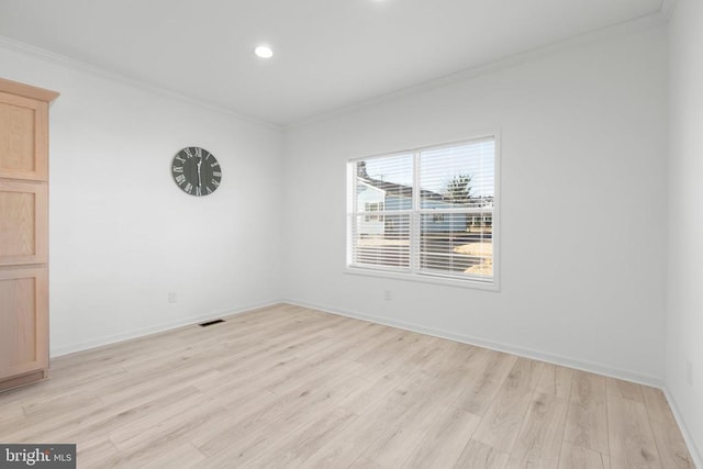 spare room with light wood-style flooring, visible vents, baseboards, and ornamental molding