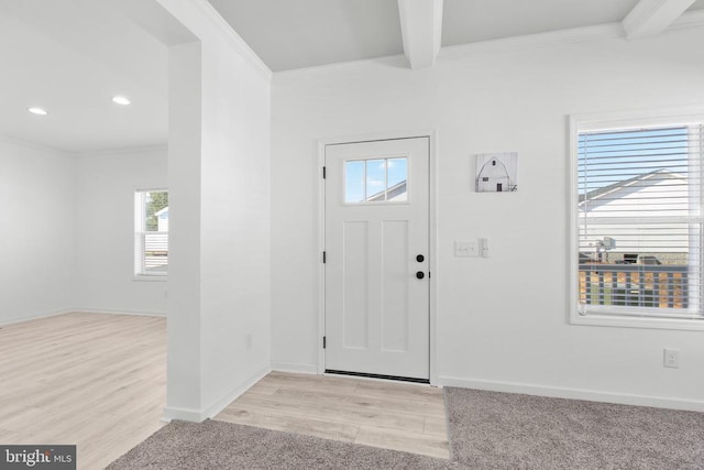 foyer entrance featuring beam ceiling, light wood finished floors, baseboards, and ornamental molding