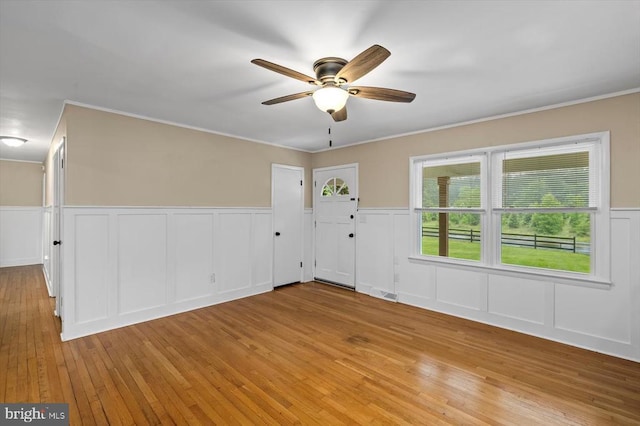 7615 Morris Rd, Spotsylvania, VA 22551 - spare room with light wood-type flooring, a ceiling fan, a decorative wall, a wainscoted wall, and ornamental molding