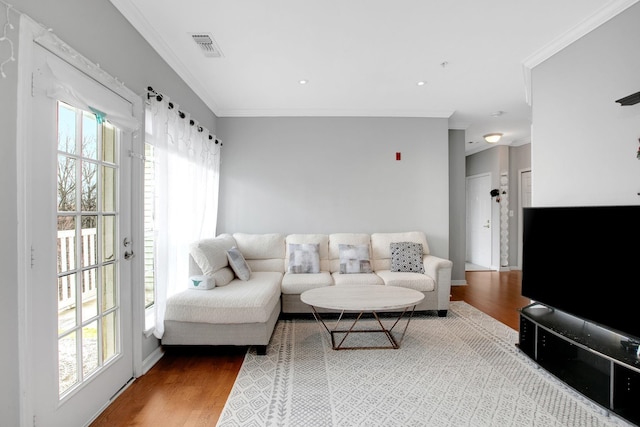 living room featuring visible vents, a healthy amount of sunlight, crown molding, and wood finished floors