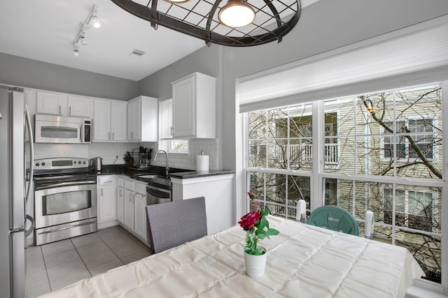 kitchen featuring light tile patterned floors, visible vents, a sink, appliances with stainless steel finishes, and white cabinetry