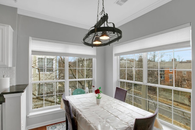 dining area with a notable chandelier, visible vents, crown molding, and baseboards