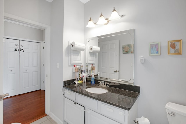 bathroom with vanity, toilet, baseboards, and tile patterned flooring