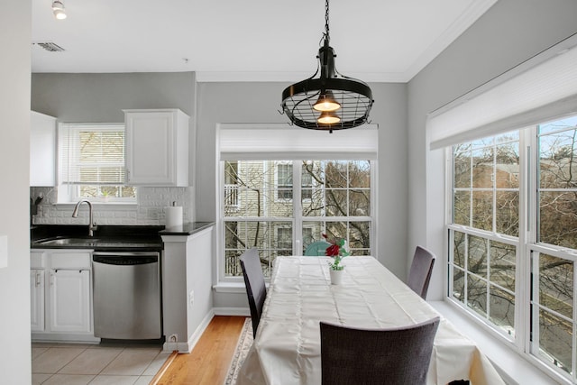 dining room featuring visible vents, light wood-type flooring, baseboards, and ornamental molding