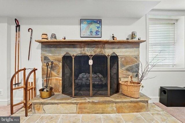 detailed view of a fireplace, baseboards, and carpet flooring