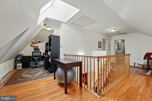 bonus room with vaulted ceiling, light wood finished floors, a desk, and a baseboard heating unit