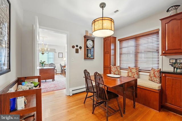 dining room with light wood finished floors, a chandelier, and baseboard heating