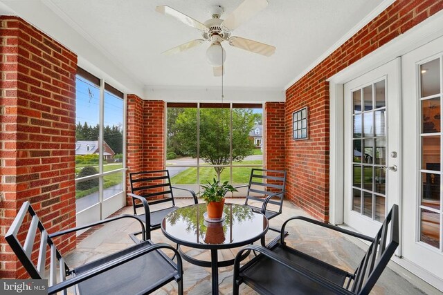 sunroom with ornamental molding, brick wall, french doors, and ceiling fan