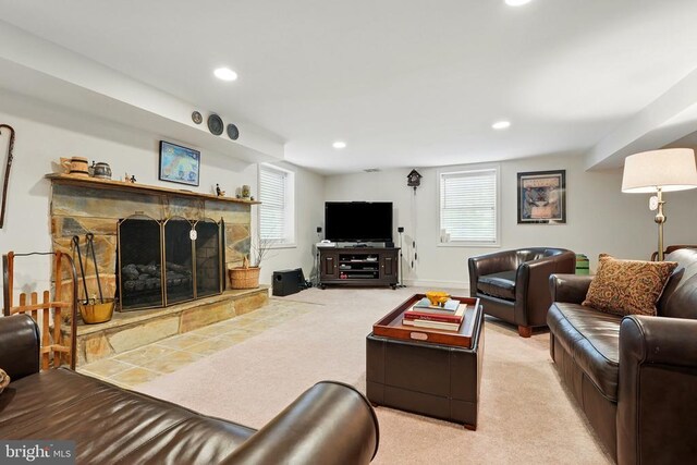 living area featuring light carpet, recessed lighting, and a stone fireplace