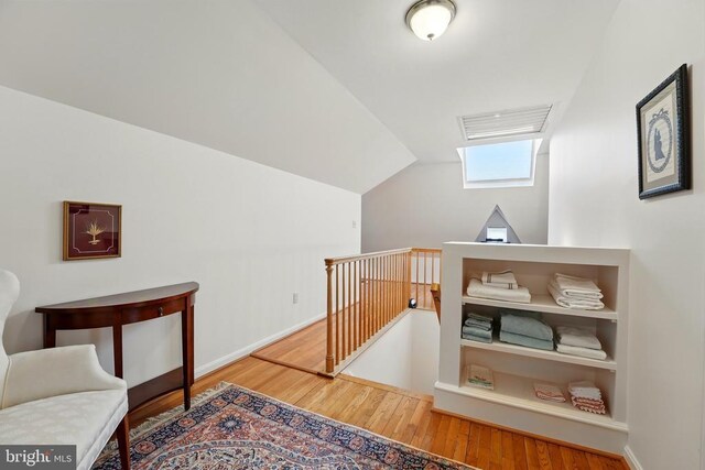 living area featuring an upstairs landing, wood finished floors, lofted ceiling, and baseboards