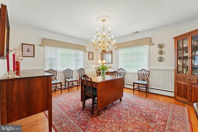 dining room with baseboard heating, healthy amount of natural light, a chandelier, a wainscoted wall, and ornamental molding