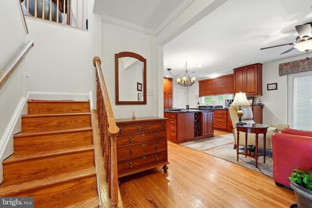 staircase featuring plenty of natural light, wood finished floors, a chandelier, a ceiling fan, and crown molding