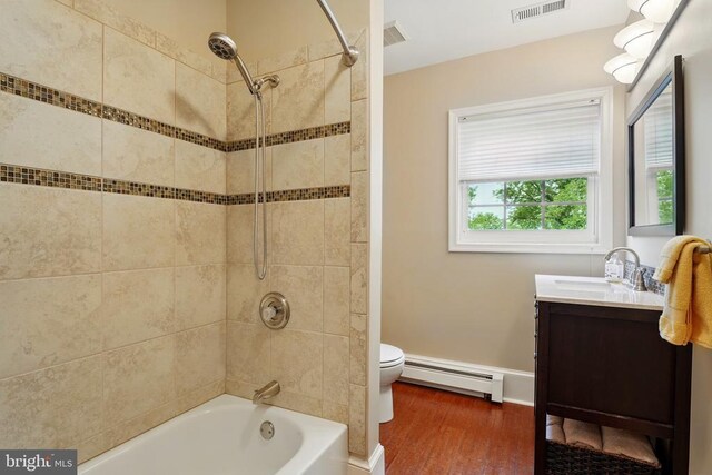 bathroom with a baseboard heating unit, vanity, wood finished floors, shower / bath combination, and toilet
