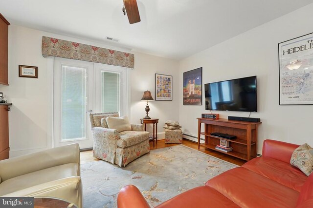 living area with a baseboard radiator, wood finished floors, ceiling fan, and baseboards