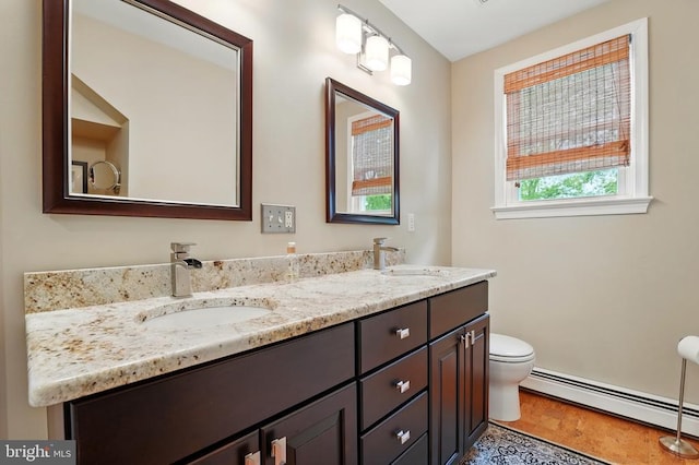 bathroom featuring a baseboard radiator, toilet, double vanity, and wood finished floors