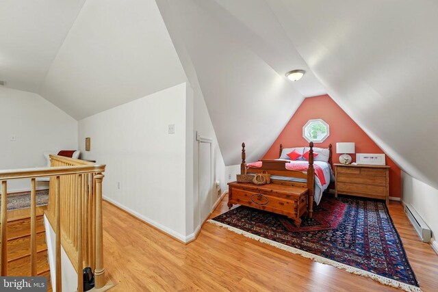 bedroom featuring wood finished floors, lofted ceiling, a baseboard radiator, and baseboards