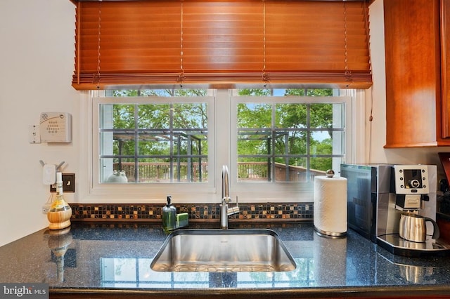 kitchen with a sink, backsplash, healthy amount of natural light, and dark stone counters